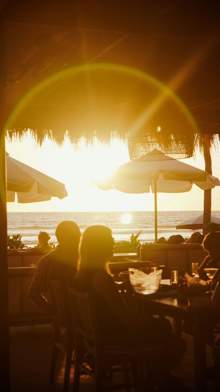Guests dining on the beach at sunset